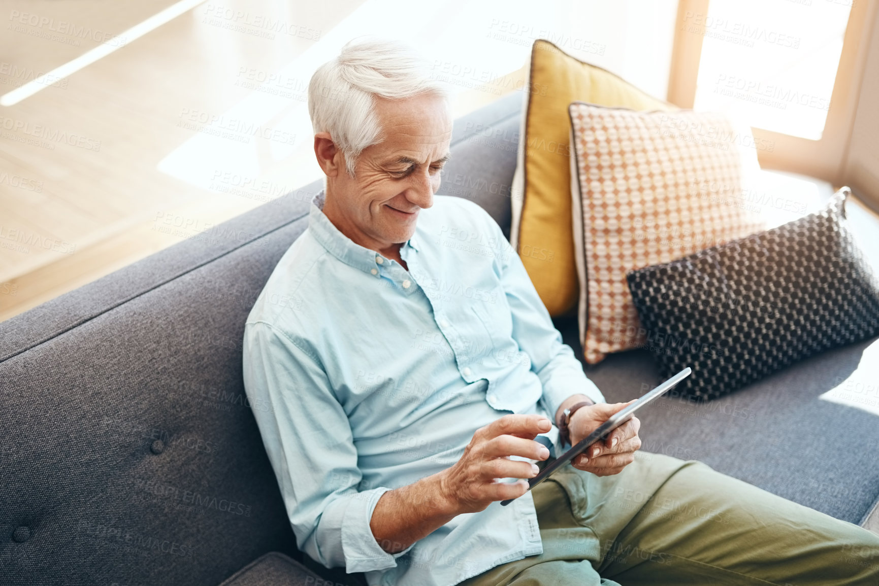 Buy stock photo Senior man, technology and retirement in home for typing email, communication and reading online news. Elderly person, tablet and relax on sofa in lounge for bills payment, webinar or streaming movie