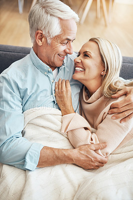 Buy stock photo Hug, happy and mature couple in blanket with love, healthy relationship and relax with partner in home on sofa. Smile, senior man and woman embrace together for connection, support and cozy in lounge