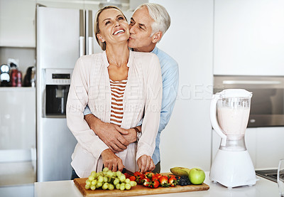 Buy stock photo Cropped shot of a handsome mature man embracing his wife while she prepares a healthy meal at home