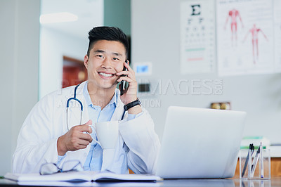 Buy stock photo Cropped portrait of a young male doctor making a call while working in a hospital
