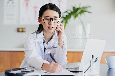 Buy stock photo Cropped shot of a young female doctor making notes while working in a hospital