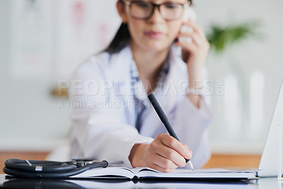 Buy stock photo Cropped shot of a young female doctor making notes while working in a hospital