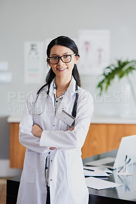 Buy stock photo Cropped portrait of a young female doctor standing with her arms folded in a hospital
