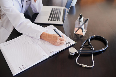 Buy stock photo High angle shot of an unrecognizable female doctor making notes while working in a hospital