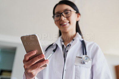 Buy stock photo Low angle shot of a young female doctor sending a text while working in the hospital