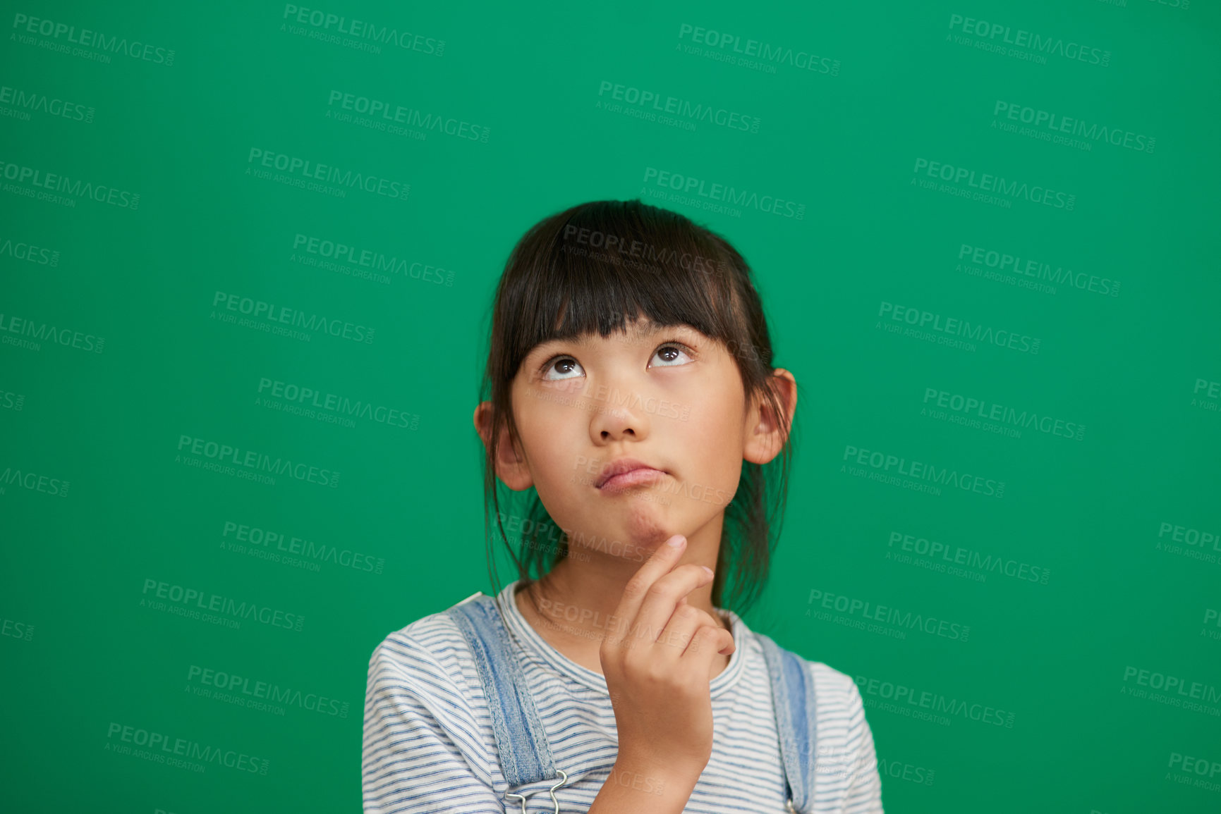 Buy stock photo Studio shot of an adorable little girl standing and contemplating against a green background