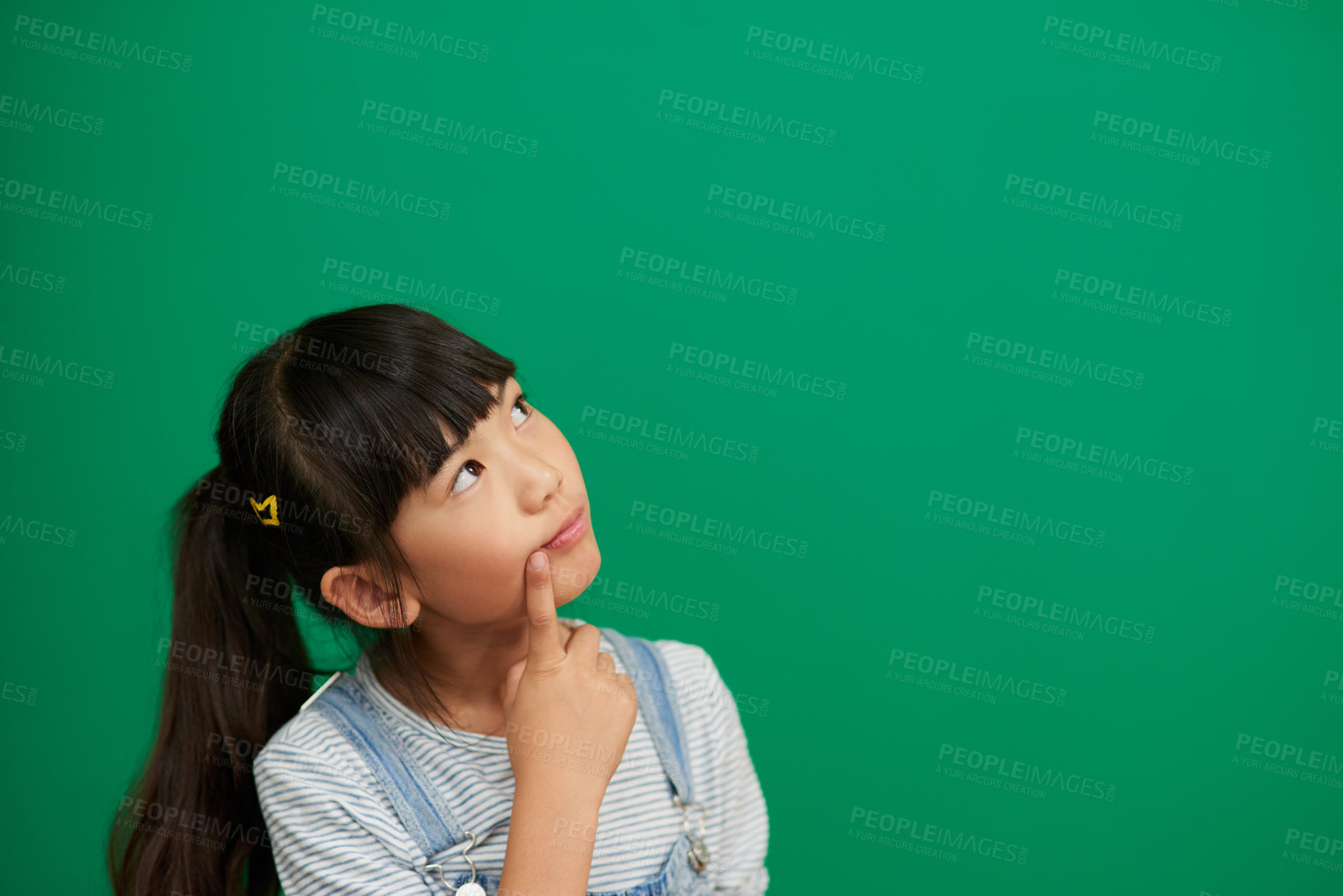 Buy stock photo Studio shot of an adorable little girl standing and contemplating against a green background