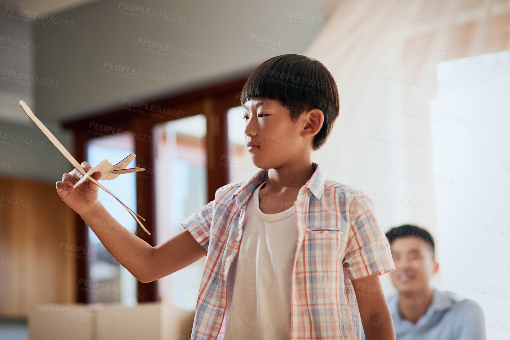 Buy stock photo Shot of a little boy playing with a paper plane at home