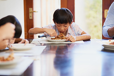Buy stock photo Shot of a little boy enjoying a meal with his family at home