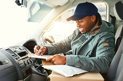 Buy stock photo Shot of a courier writing on a clipboard while sitting in a delivery van