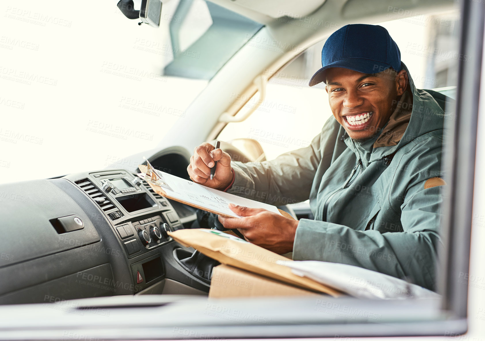 Buy stock photo Portait of a courier writing on a clipboard while sitting in a delivery van
