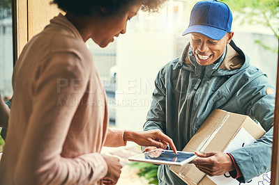 Buy stock photo Shot of a woman using a digital tablet to sign for her delivery from the courier
