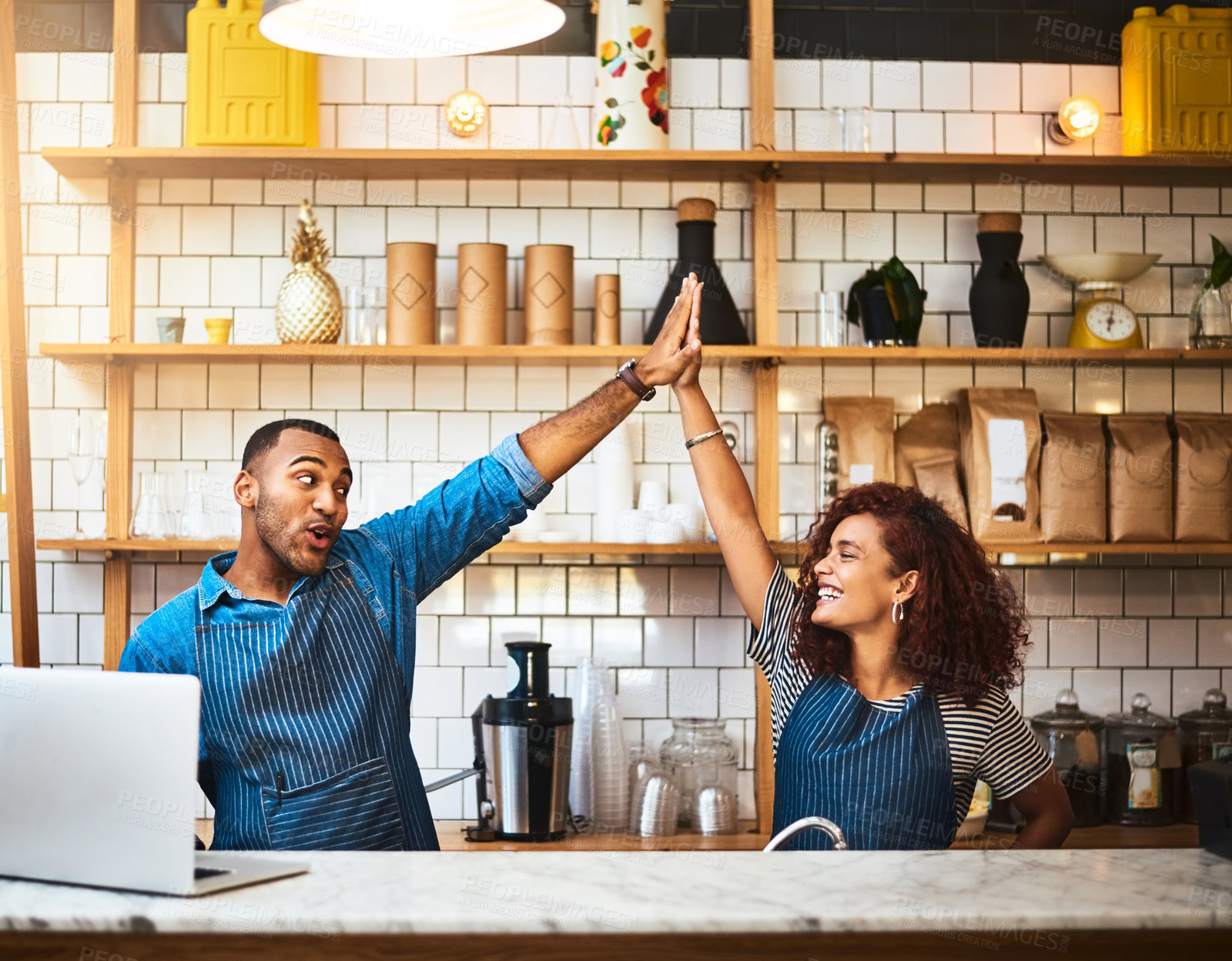 Buy stock photo Cropped shot of an affectionate young couple high fiving while standing in their coffee shop
