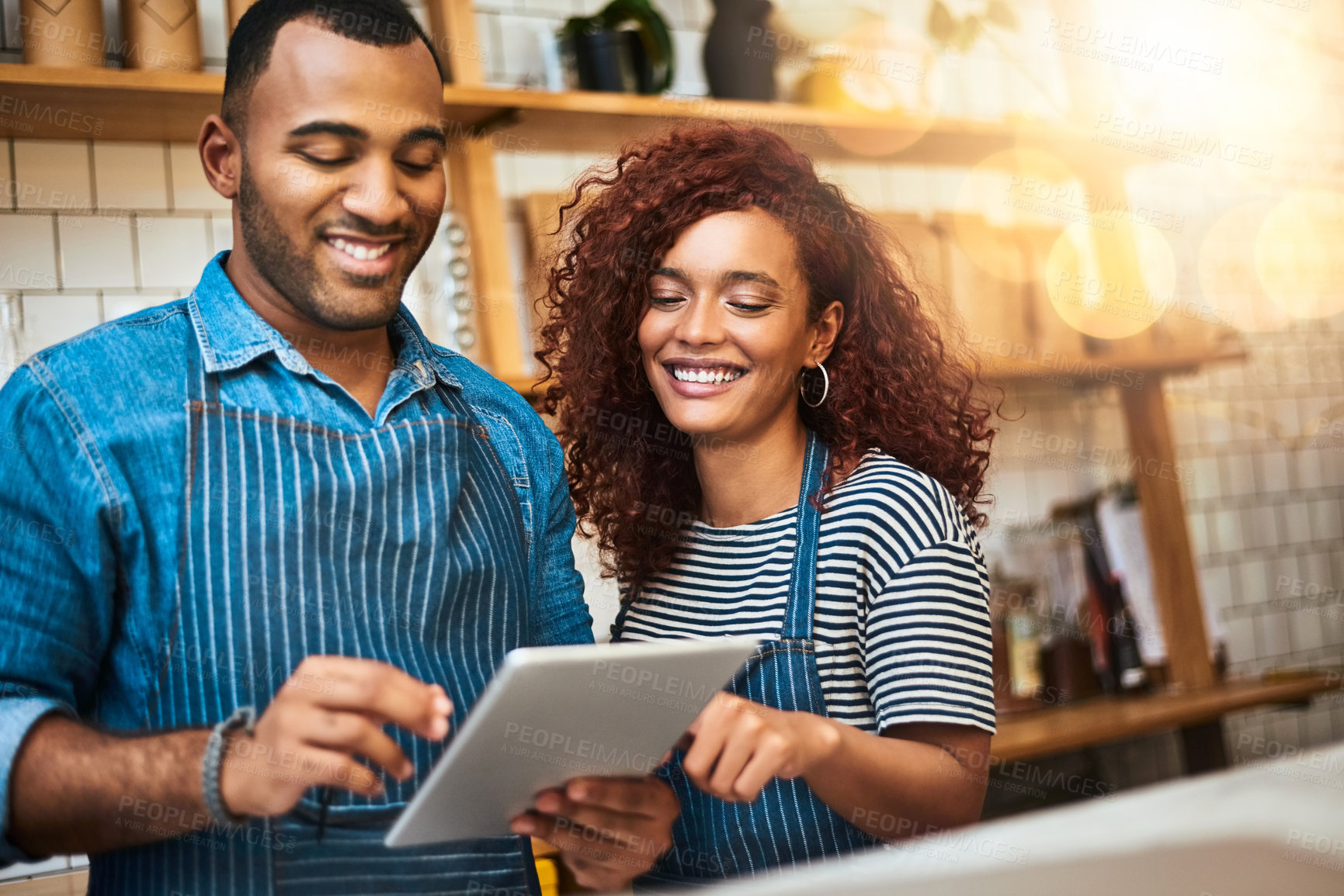 Buy stock photo Cropped shot of an affectionate young couple working on a tablet in their coffee shop