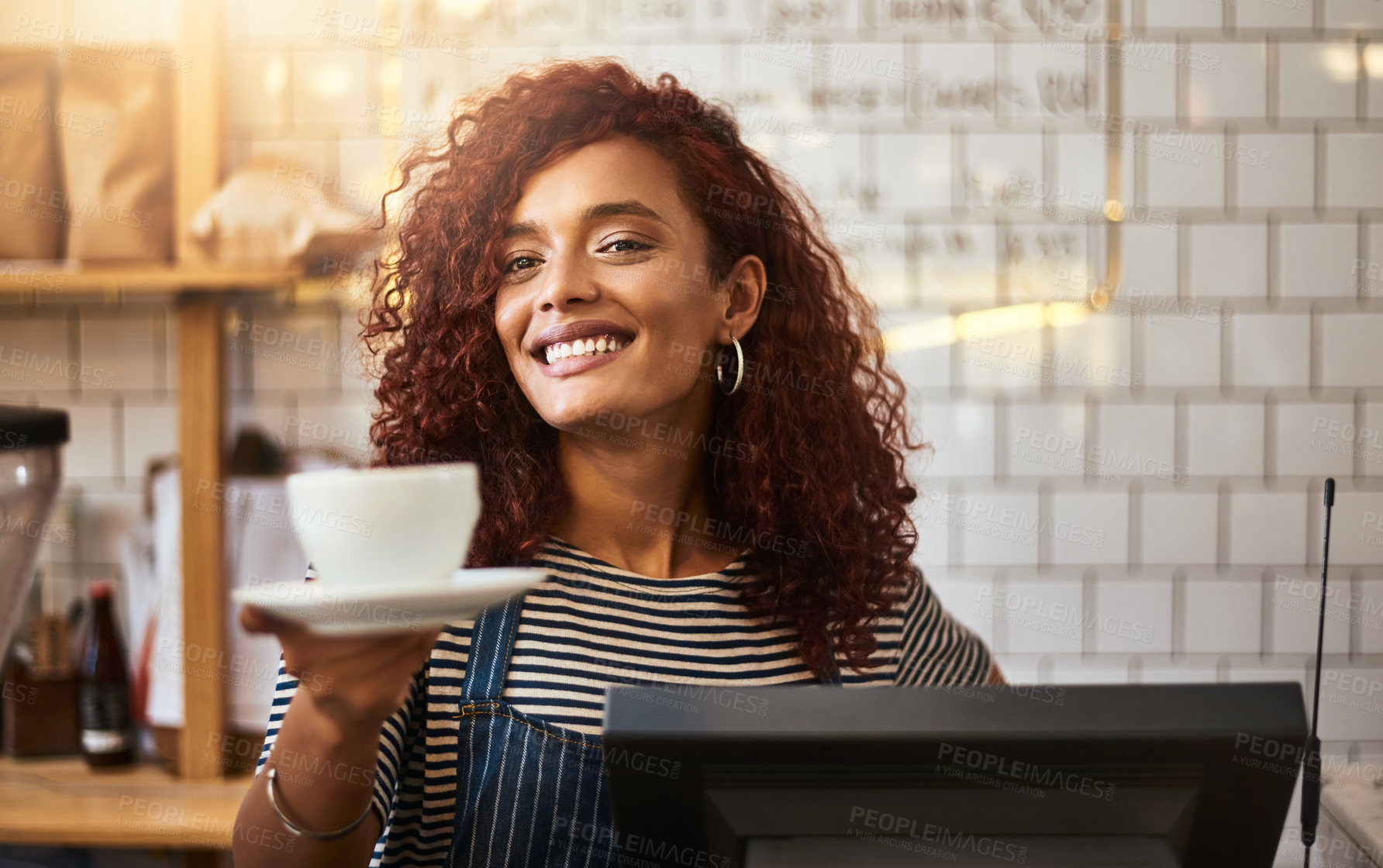 Buy stock photo Shot of a young barista holding a cup of coffee in a cafe