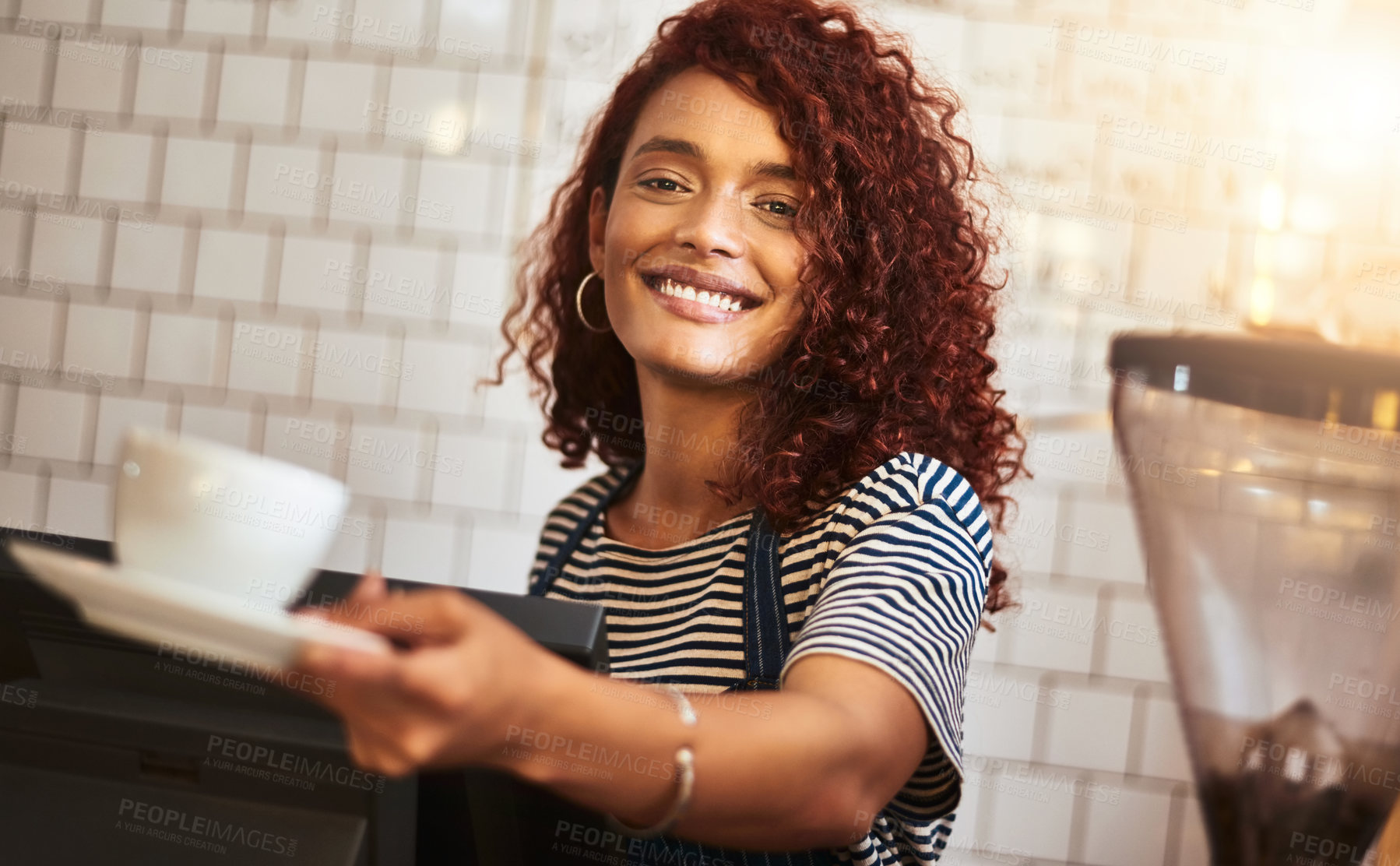 Buy stock photo Portrait of a young barista holding a cup of coffee in a cafe