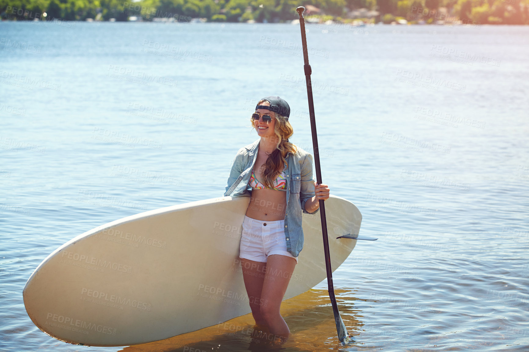 Buy stock photo Shot of an attractive young woman paddle boarding on a lake