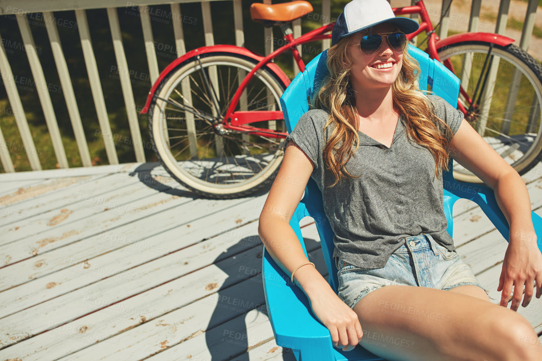 Buy stock photo Shot of an attractive young woman relaxing on a deck chair outdoors