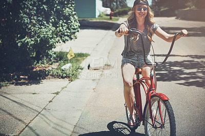 Buy stock photo Shot of an attractive young woman riding a bicycle outdoors