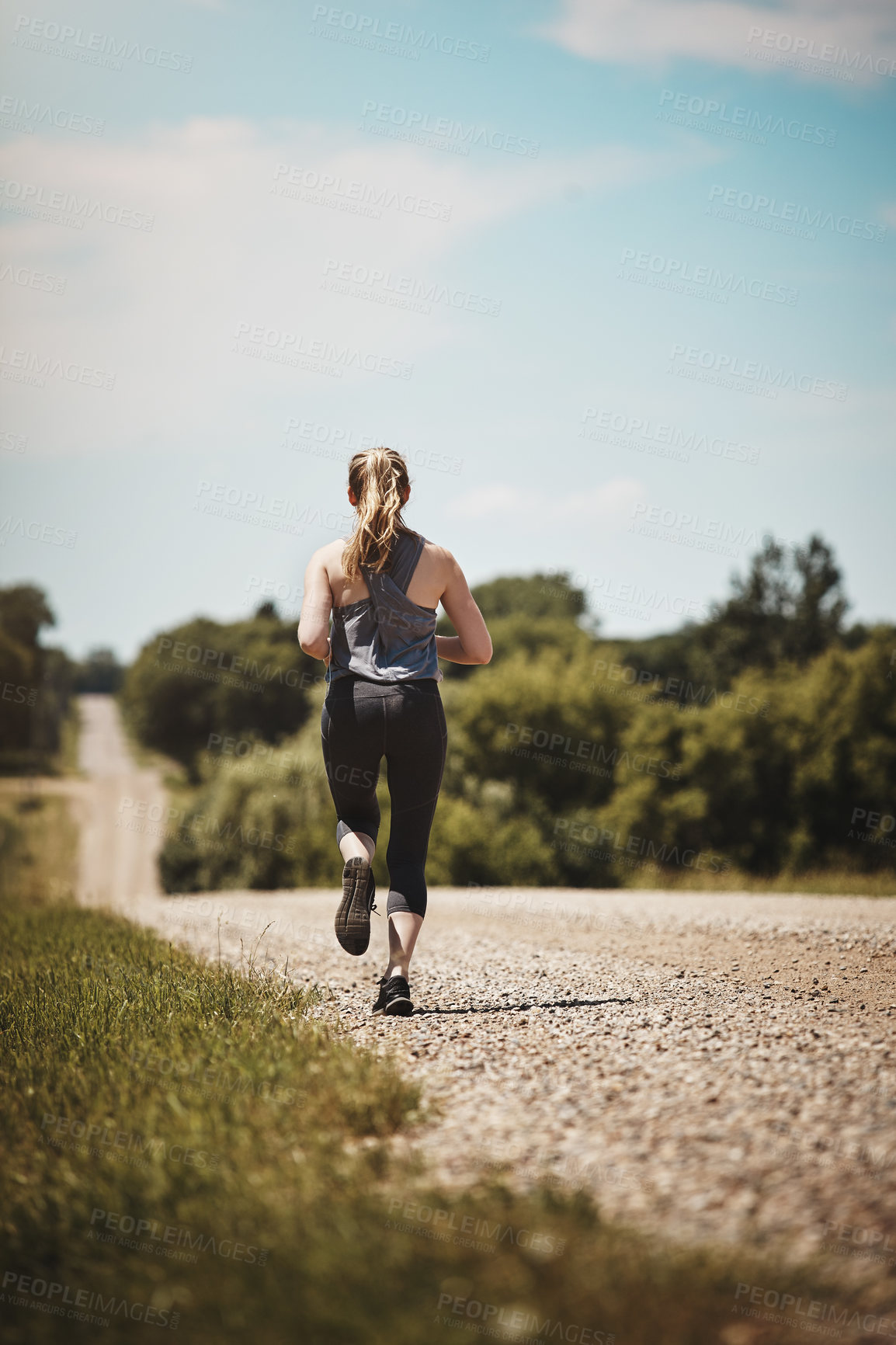 Buy stock photo Rearview shot of a young woman out on a trail run