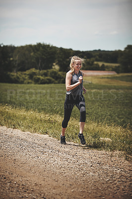 Buy stock photo Shot of a young woman out on a trail run