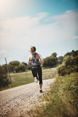 Buy stock photo Rearview shot of a young woman out on a trail run