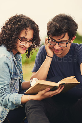 Buy stock photo Cropped shot of a teenage couple reading a book together outdoors