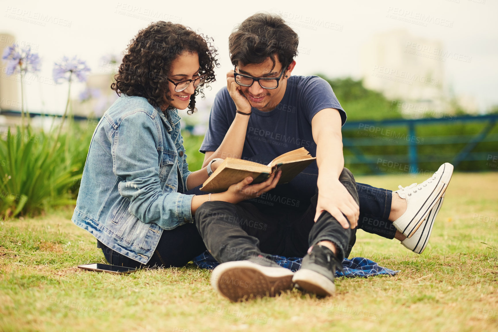 Buy stock photo Shot of a teenage couple reading a book together outdoors