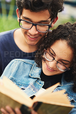 Buy stock photo Cropped shot of a teenage couple reading a book together outdoors
