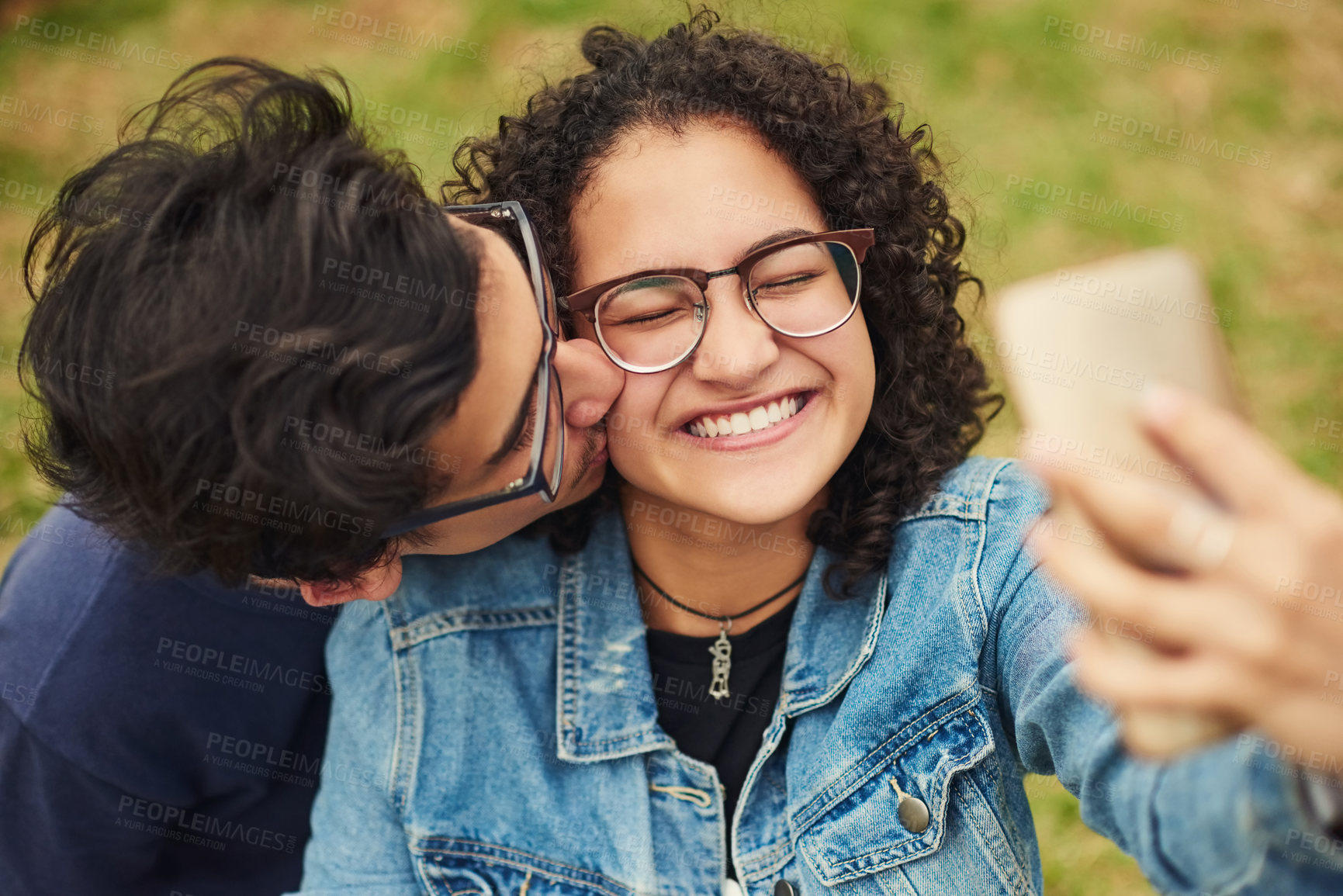 Buy stock photo Couple, happy and selfie outdoor for kiss, bonding and social media together on weekend with romance. Boy, girl and relax for relationship, memory and profile picture in park with love connection