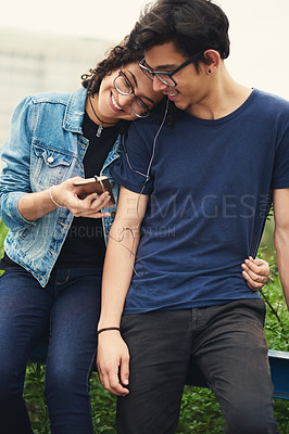 Buy stock photo Cropped shot of a teenage couple listening to music together outdoors