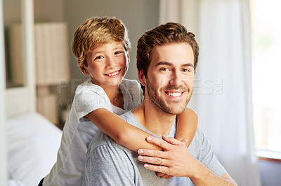 Buy stock photo Portrait of a cheerful young boy holding and leaning on his father's back at home during the day