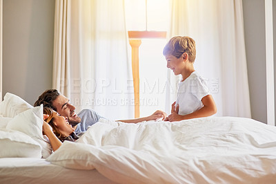 Buy stock photo Shot of a cheerful little boy trying to wake up his family in bed at home in the morning