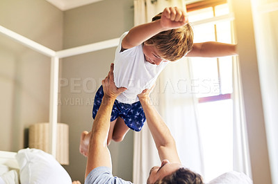 Buy stock photo Shot of a cheerful little boy being picked up by his father while playing around at home in the morning