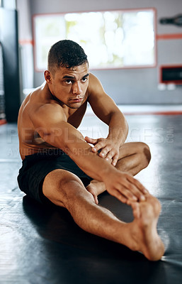 Buy stock photo Shot of a young man stretching before a fight at the gym