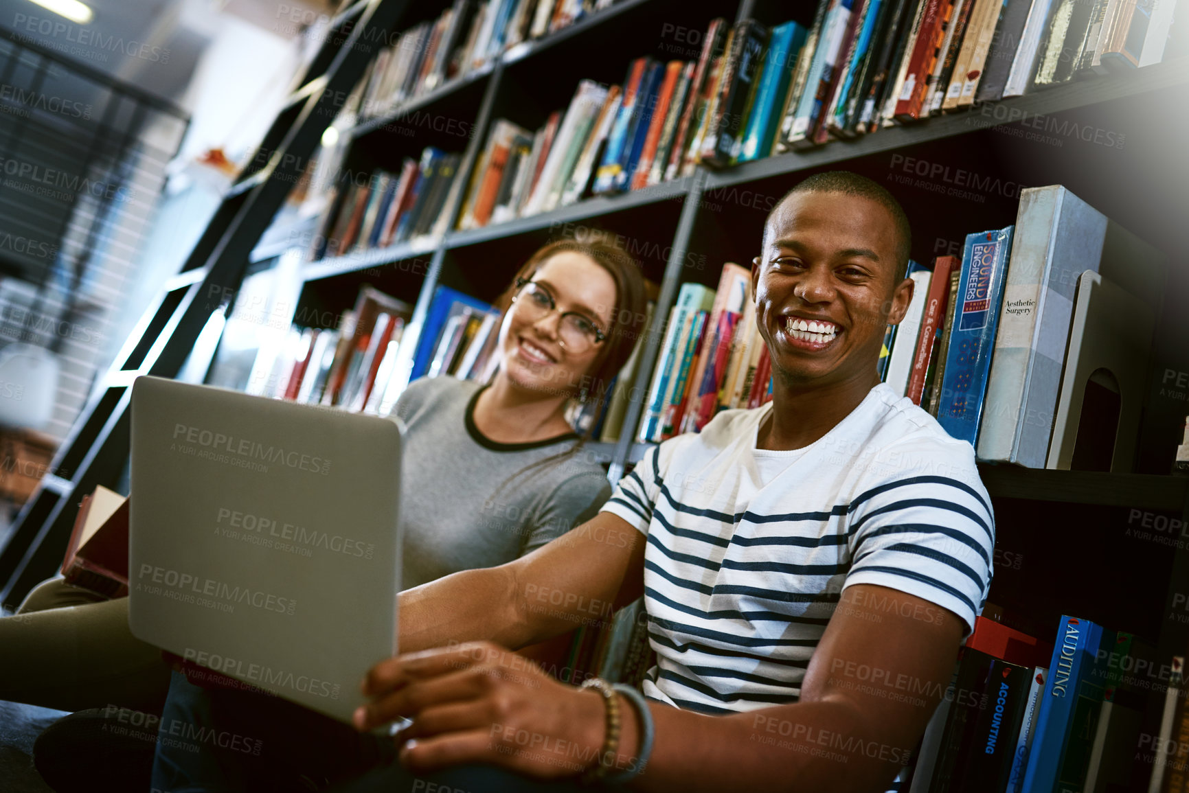 Buy stock photo Portrait of a young man and woman using a laptop together in a college library