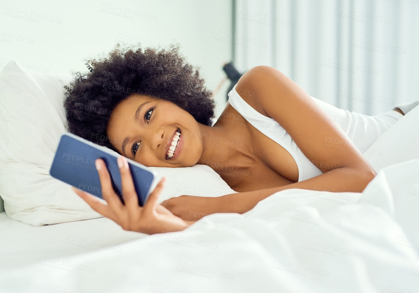 Buy stock photo Cropped shot of an attractive young woman using a cellphone in bed at home