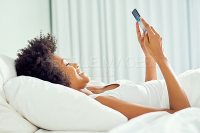 Buy stock photo Cropped shot of an attractive young woman using a cellphone in bed at home
