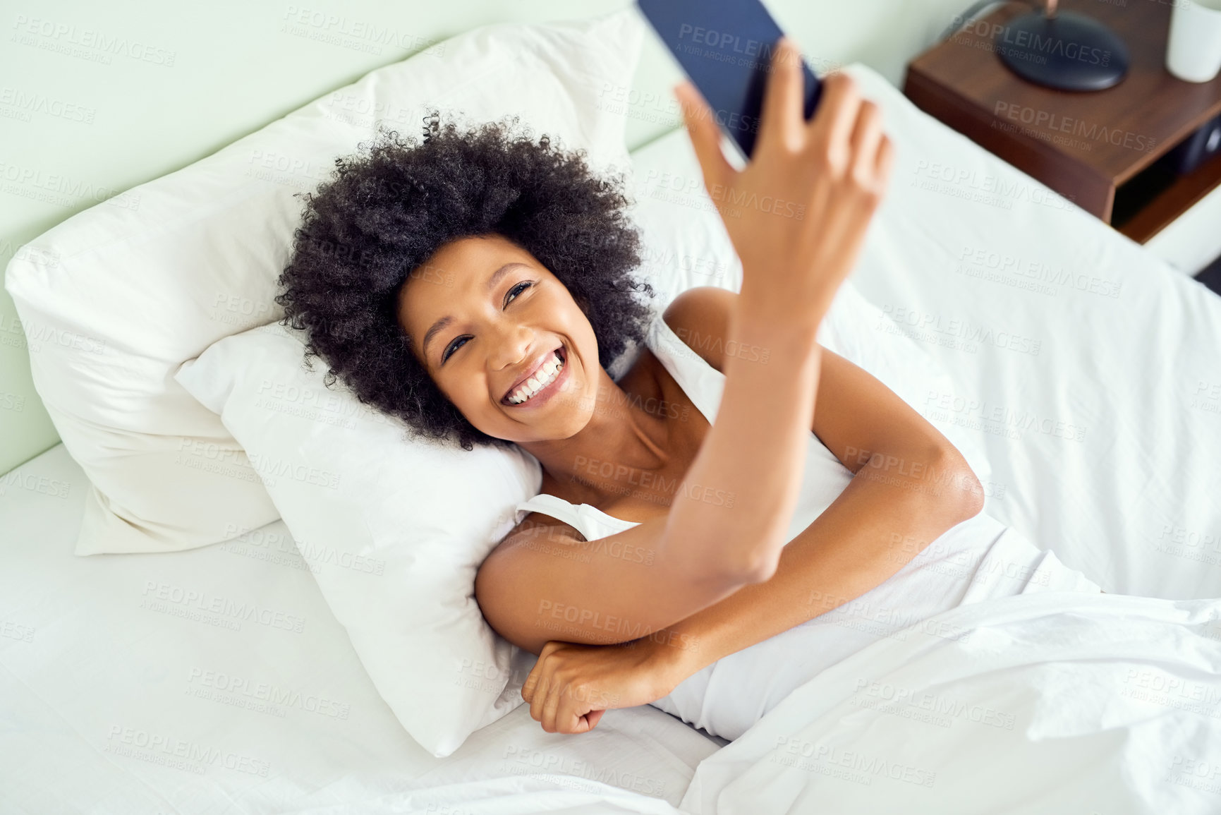 Buy stock photo Cropped shot of an attractive young woman taking a selfie in bed at home