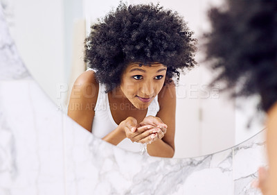 Buy stock photo Cropped shot of an attractive young woman washing her face in the bathroom at home