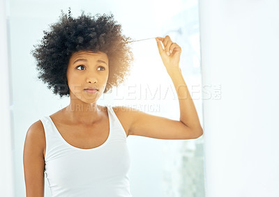 Buy stock photo Cropped shot of an attractive young woman holding her hair and looking in the mirror at home