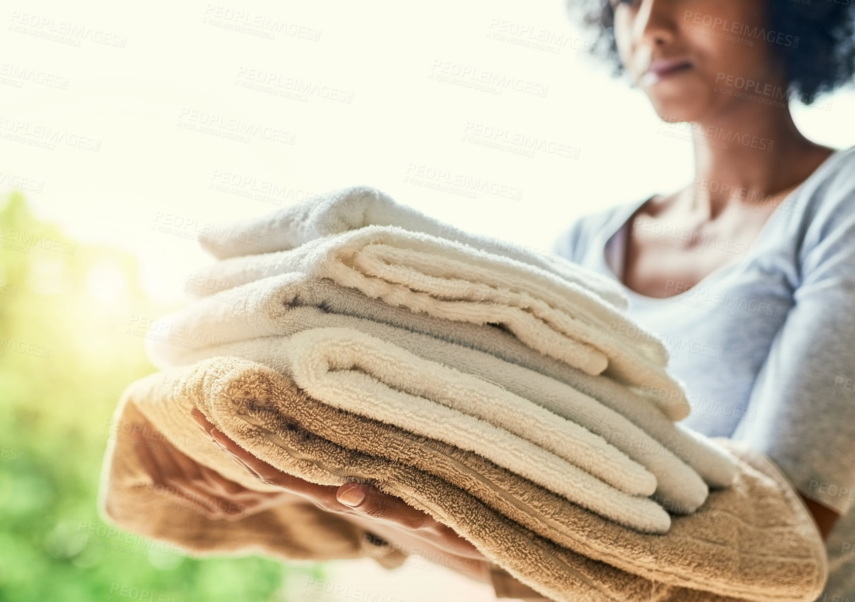 Buy stock photo Cropped shot of an unrecognizable woman holding folded towels at home
