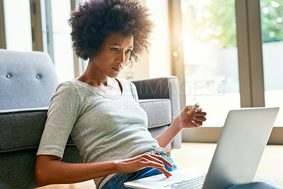 Buy stock photo Shot of an attractive young woman using her laptop to shop online at home over the weekend