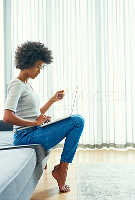 Buy stock photo Full length shot of an attractive young woman using her laptop to shop online at home over the weekend