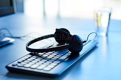 Buy stock photo Closeup shot of a headset lying on a keyboard in an office