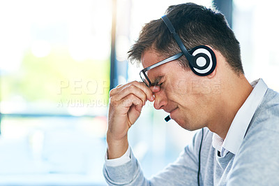 Buy stock photo Shot of a young call centre agent looking stressed out while working in an office