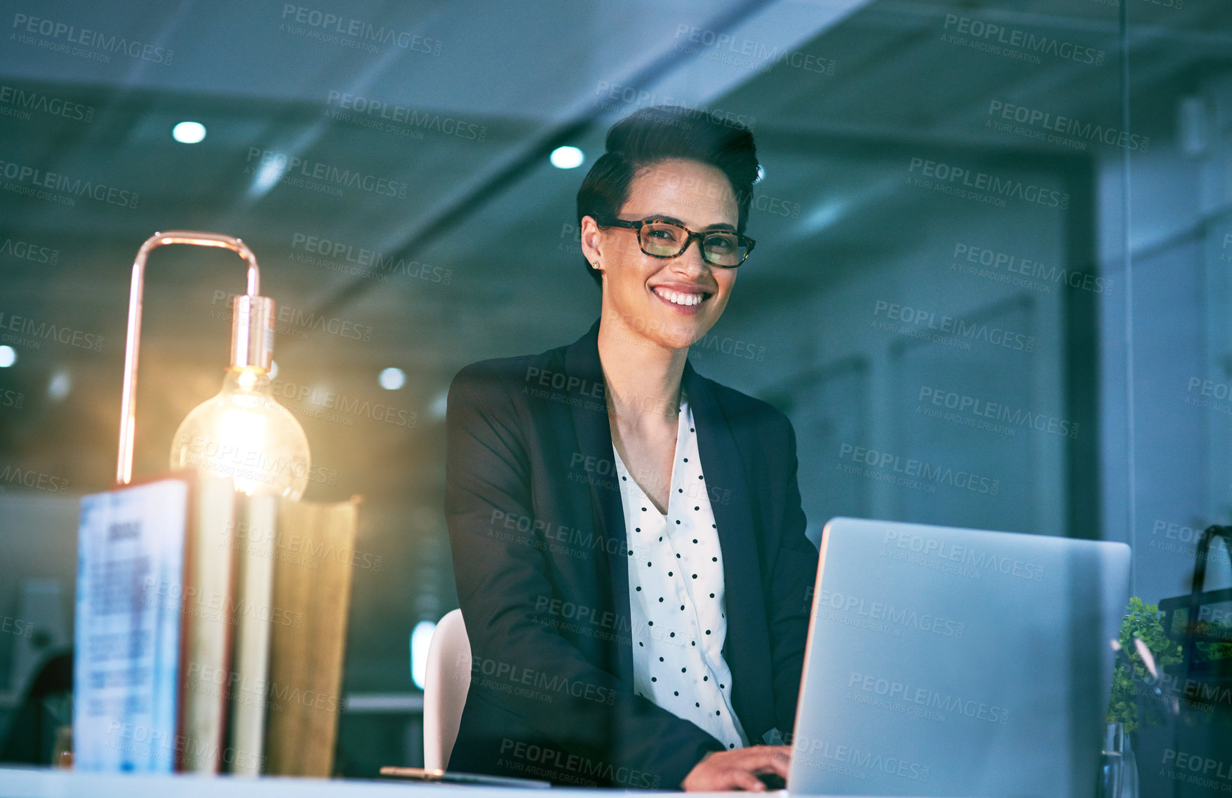 Buy stock photo Portrait of a confident businesswoman working on a laptop in an office at night
