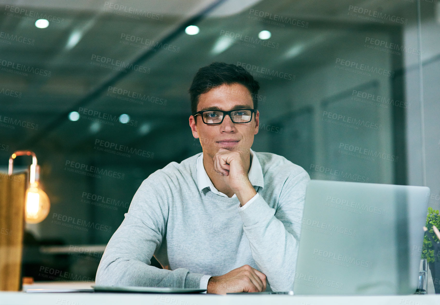 Buy stock photo Portrait of a confident young businessman working in an office at night
