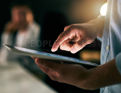 Buy stock photo Closeup shot of an unrecognizable businessman working on a digital tablet in an office at night