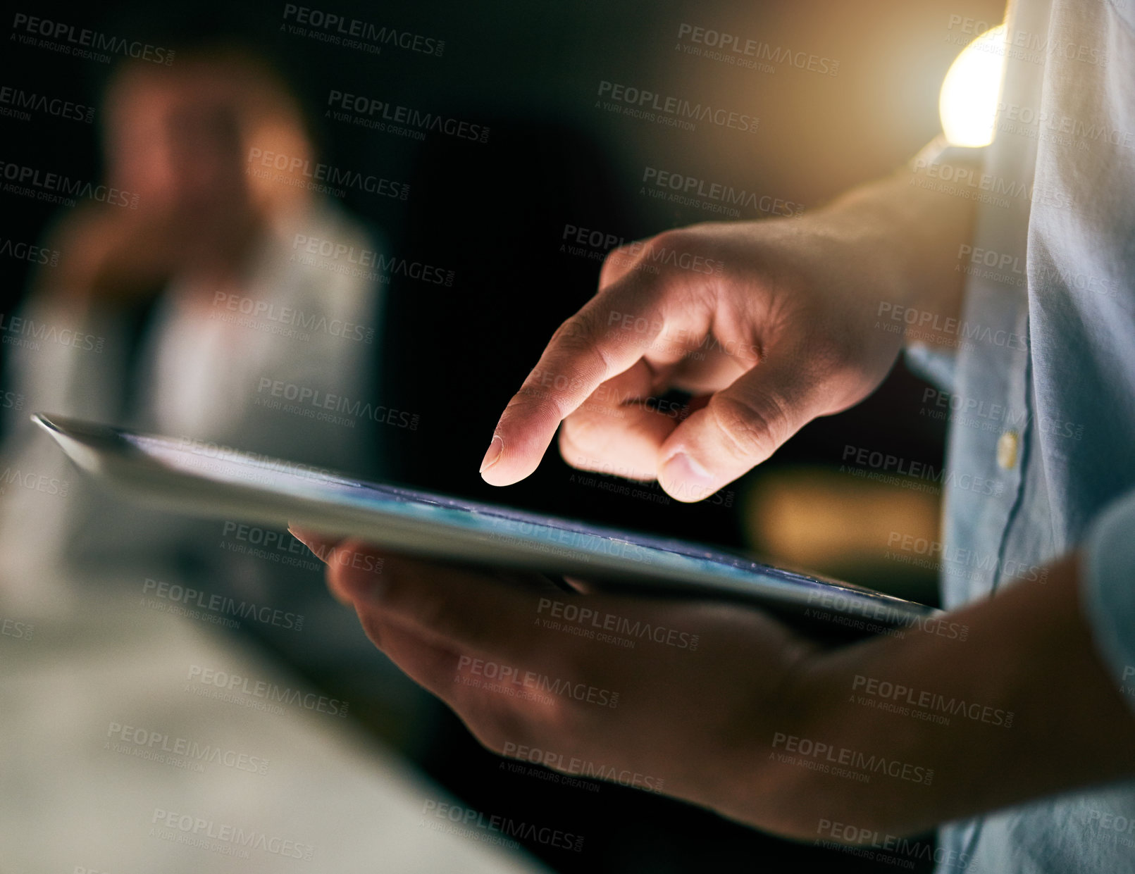Buy stock photo Closeup shot of an unrecognizable businessman working on a digital tablet in an office at night